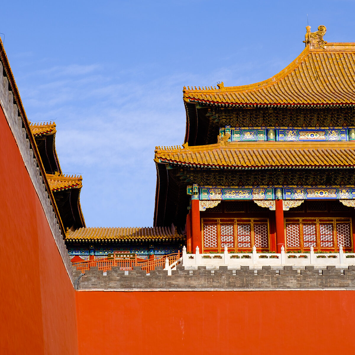 Shoes? No. A traditional Chinese building with ornate multi-tiered yellow-tiled roofs, red wooden windows, and decorative blue-green trim set against a blue sky, bordered by a bright red wall.