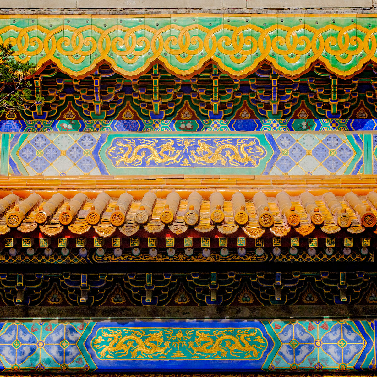Ornate, multicolored architectural details with turquoise, gold, and red patterns, dragon motifs, and decorative curved tiles on a temple facade.