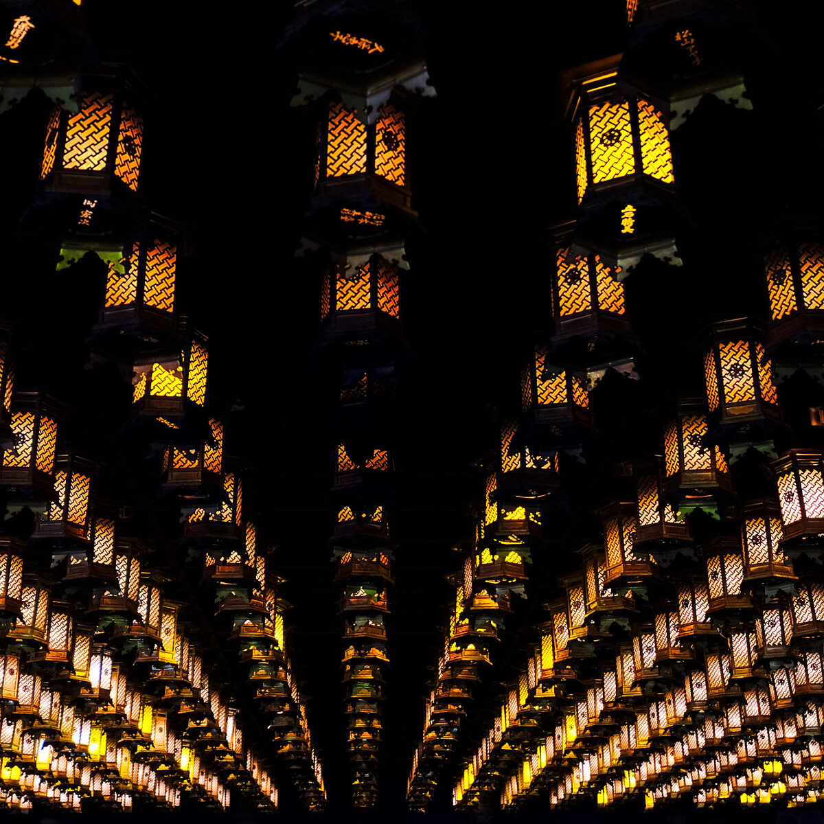 Hundreds of warm orange lanterns hang in rows from the ceiling, creating a glowing grid against a dark background.