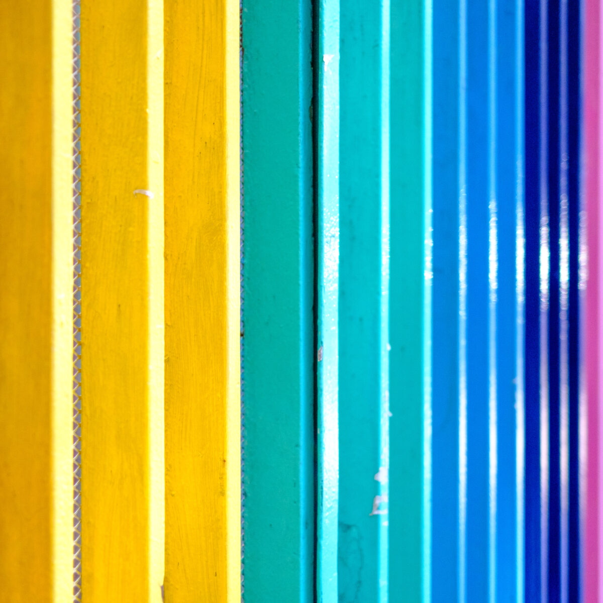Colorful vertical slats in a gradient rainbow: reds to yellows, greens to blues, with varying textures and edge details.